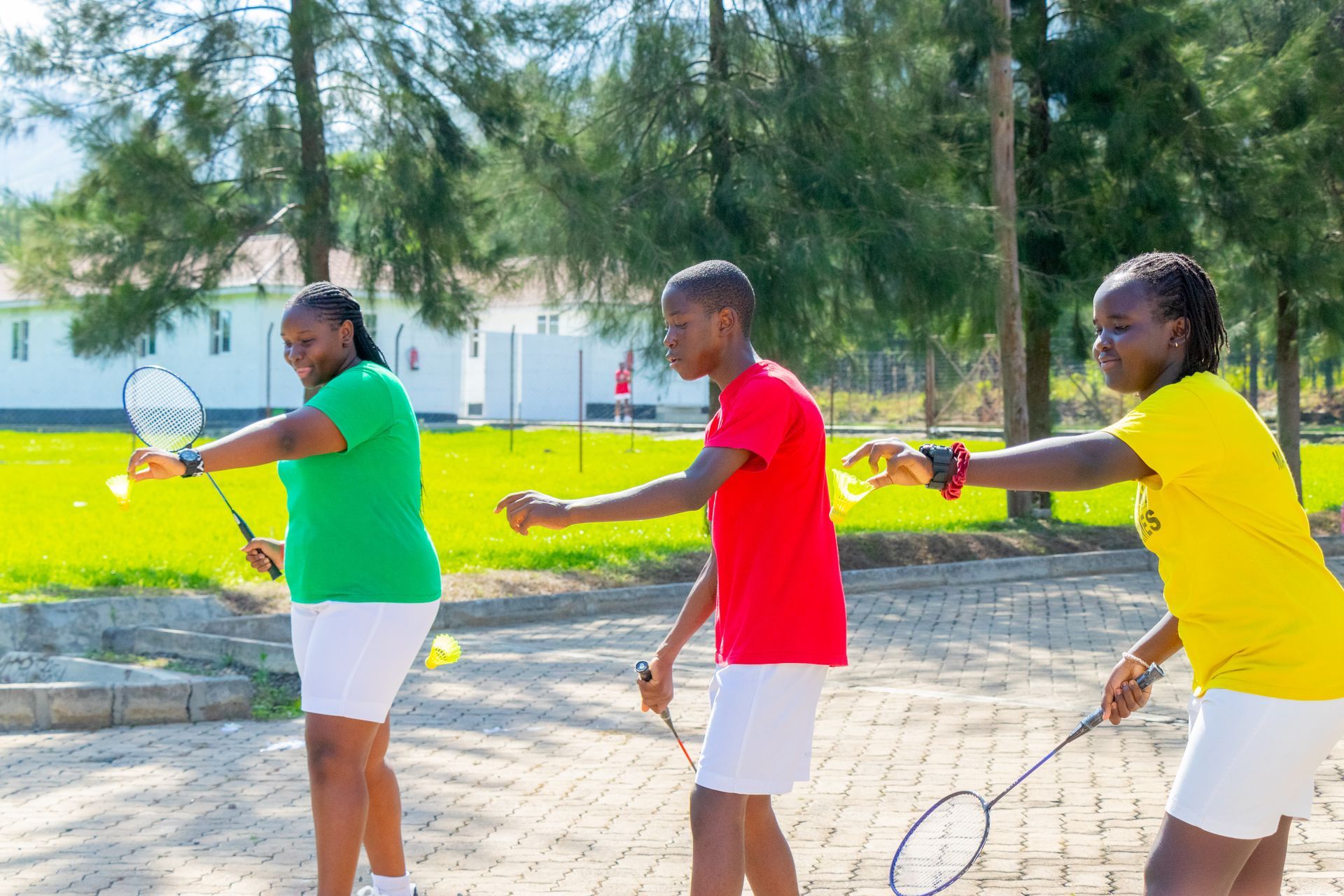 A man is holding a soccer ball in front of a group of children.