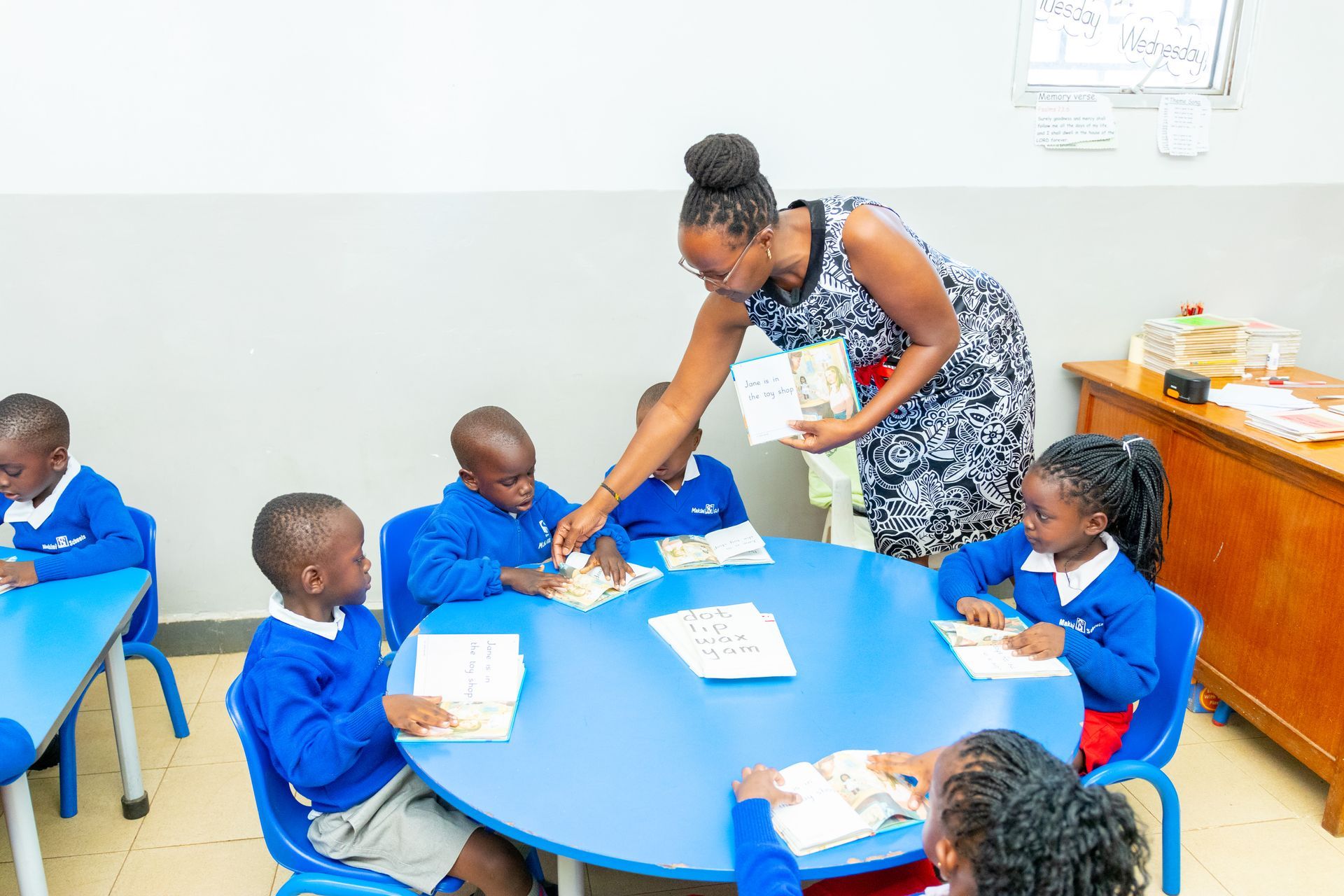 A teacher is teaching a group of children in a classroom.