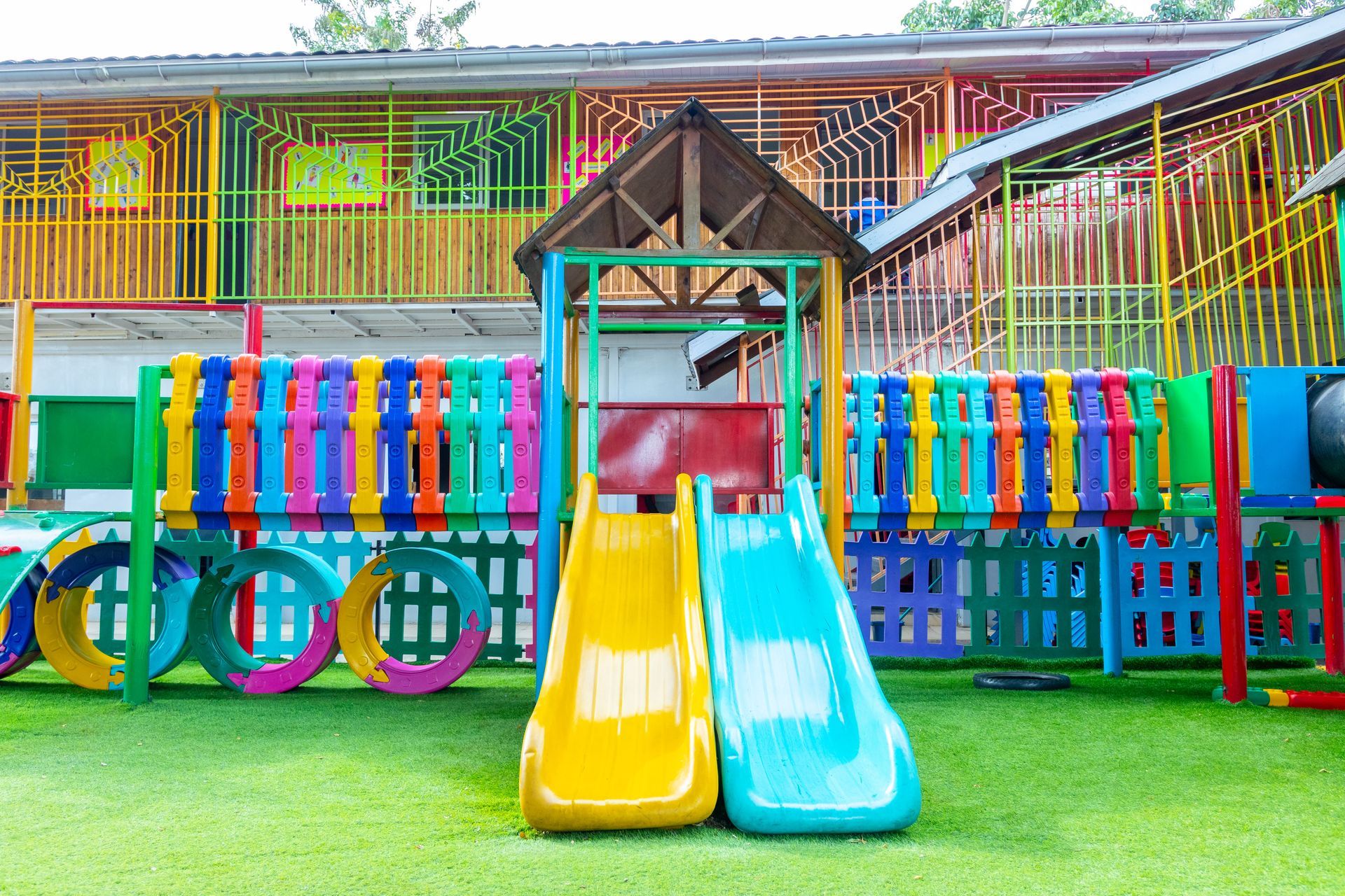 A colorful playground with two slides and a swing set.