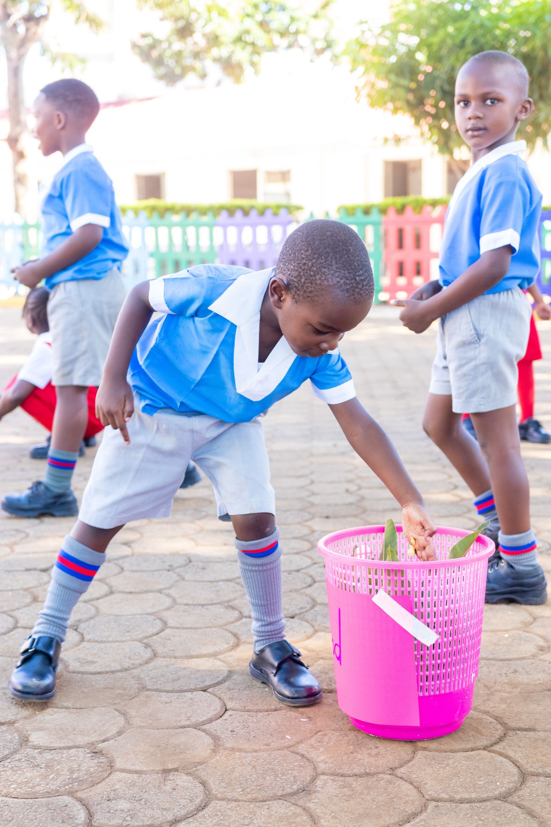 A group of children are playing with a pink bucket.