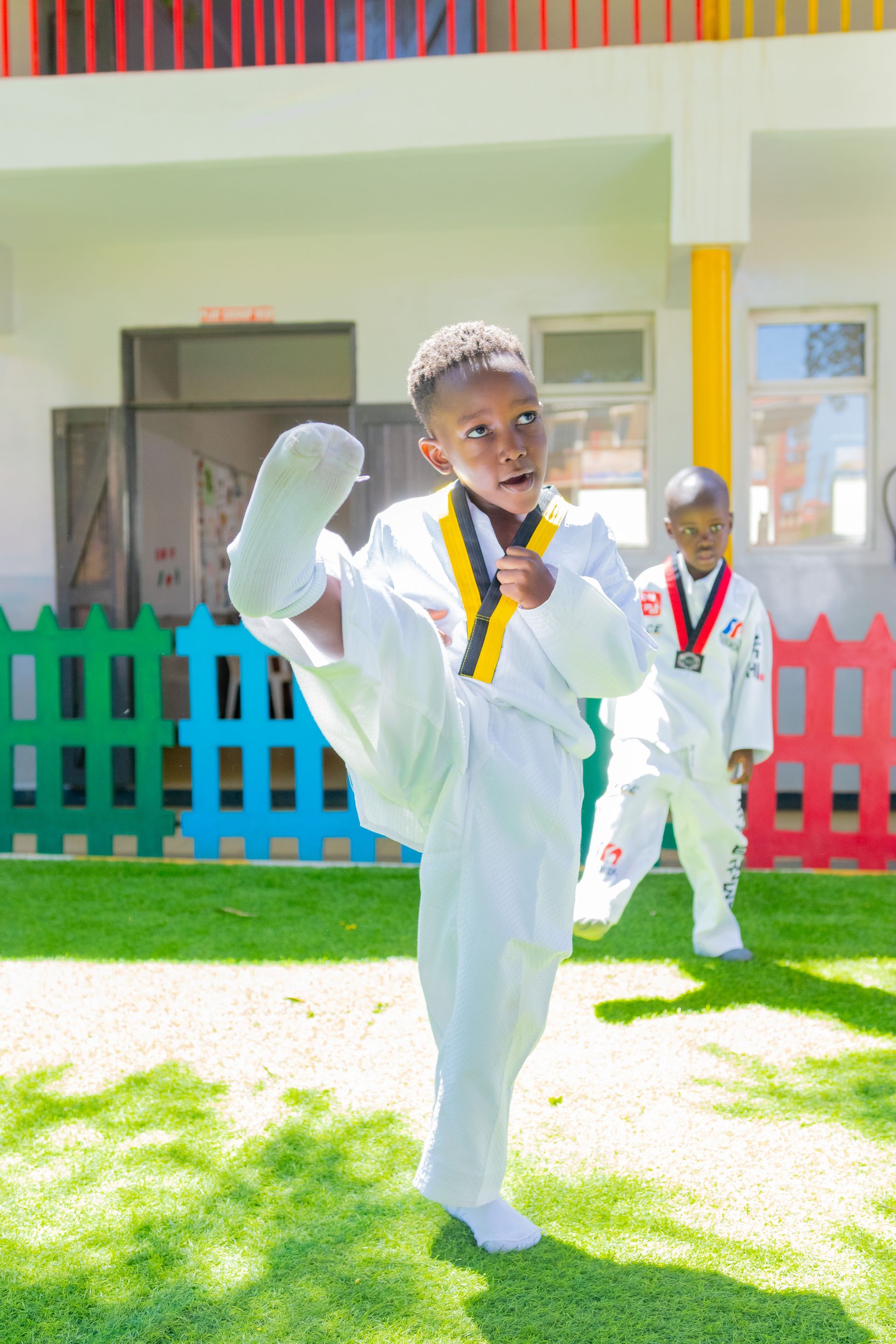 A young boy in a taekwondo uniform is kicking in the air.