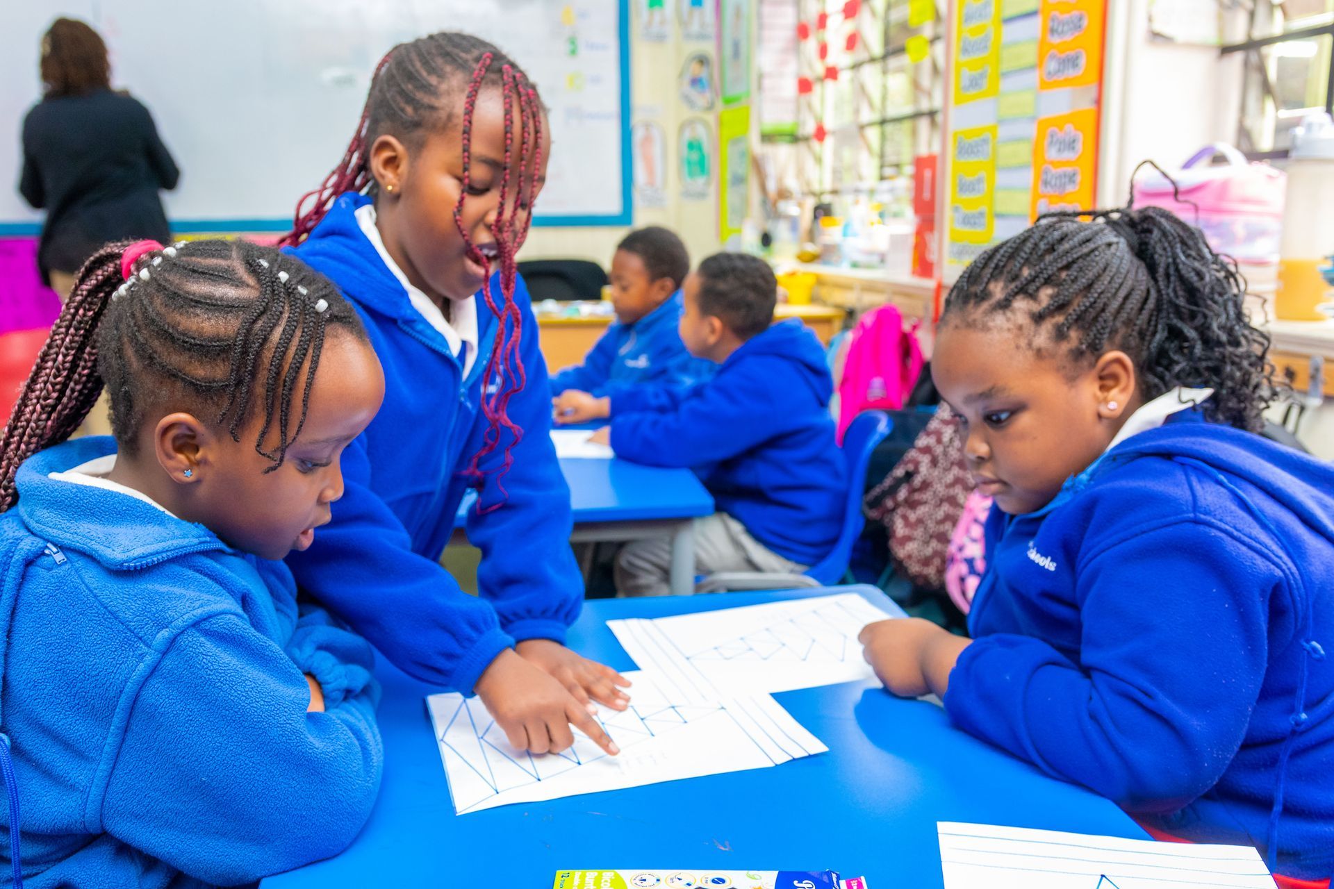 A group of children are sitting at a table in a classroom.