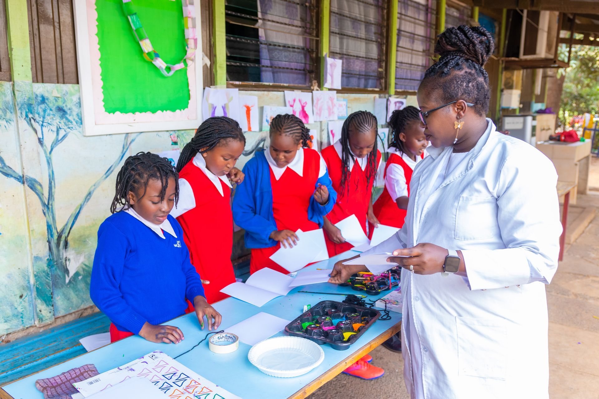 A teacher is teaching a group of children how to paint.