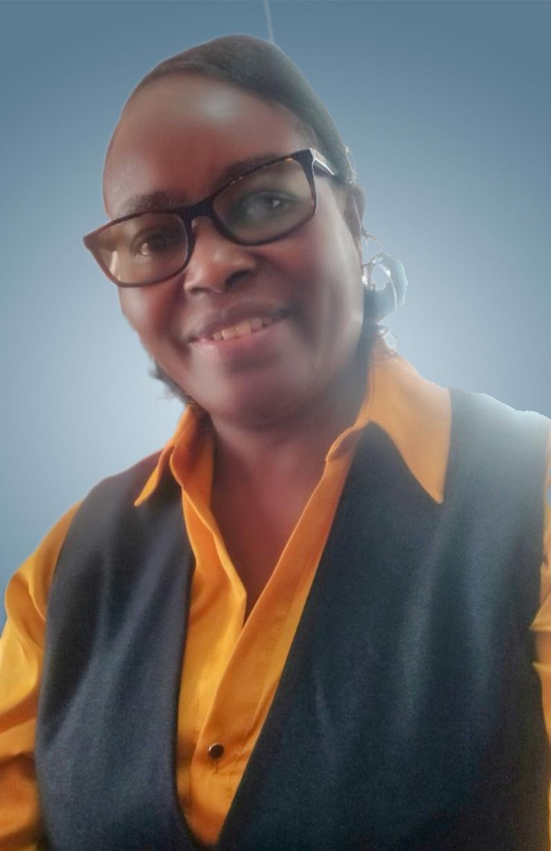 A woman wearing glasses and a yellow shirt is smiling for the camera.