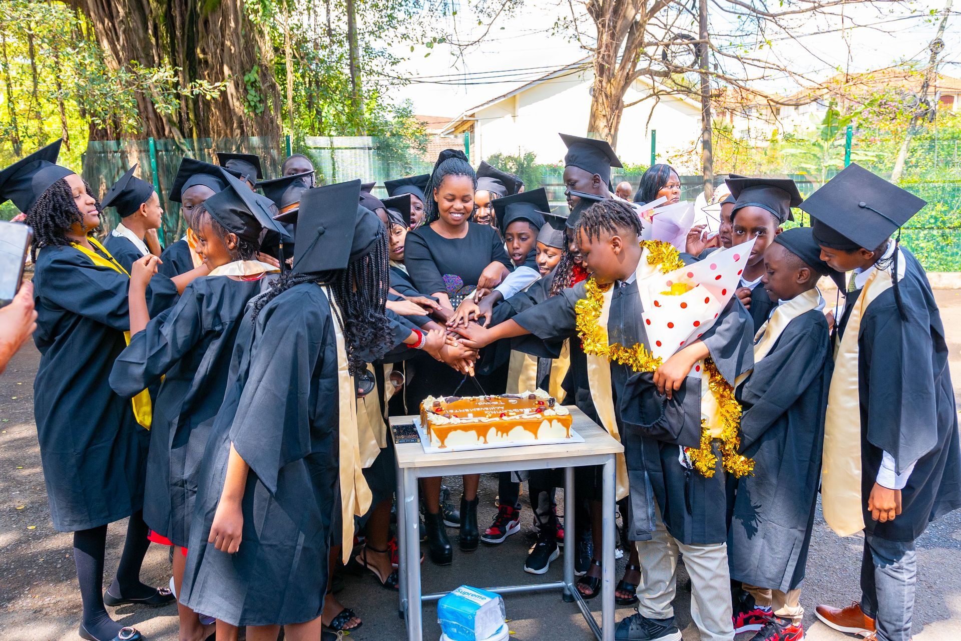 A group of graduates are standing around a table with a cake.