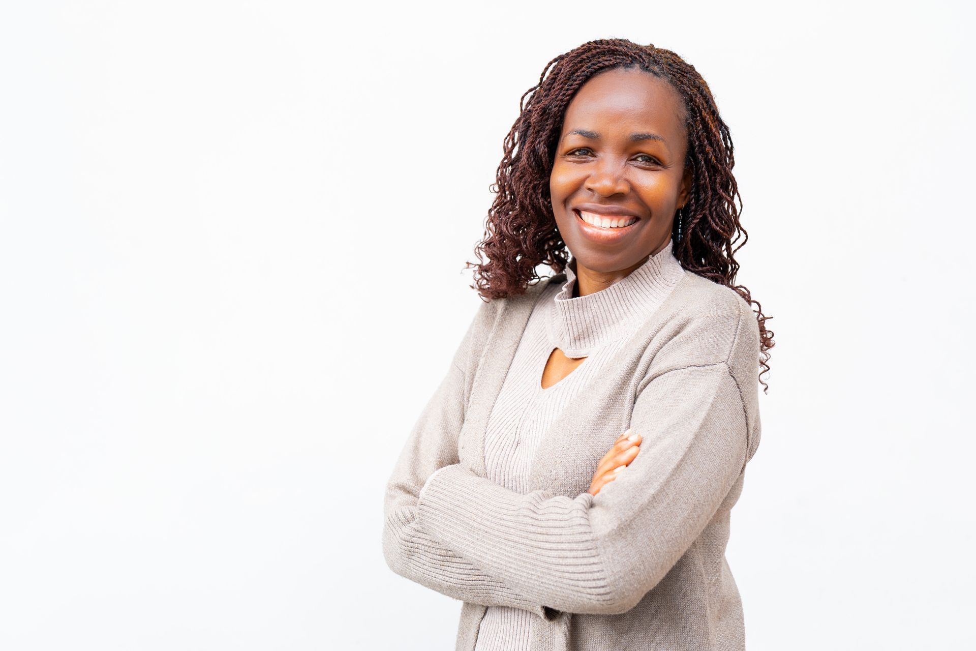 A woman is standing with her arms crossed and smiling.