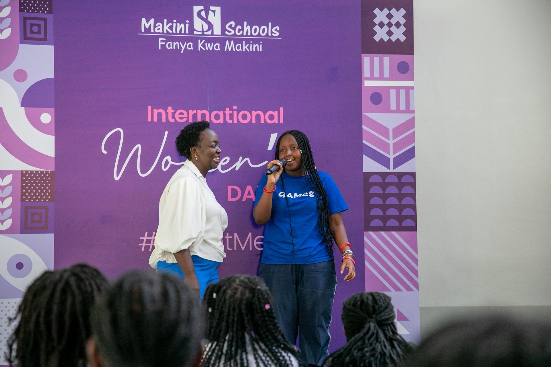 Two women are standing next to each other in front of a crowd.