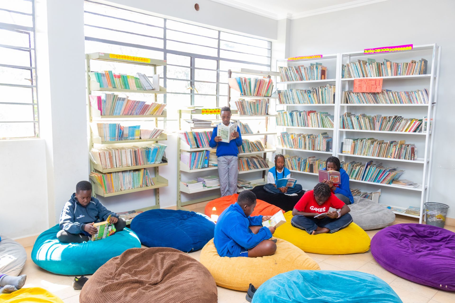 A group of people are sitting on bean bags in a library.