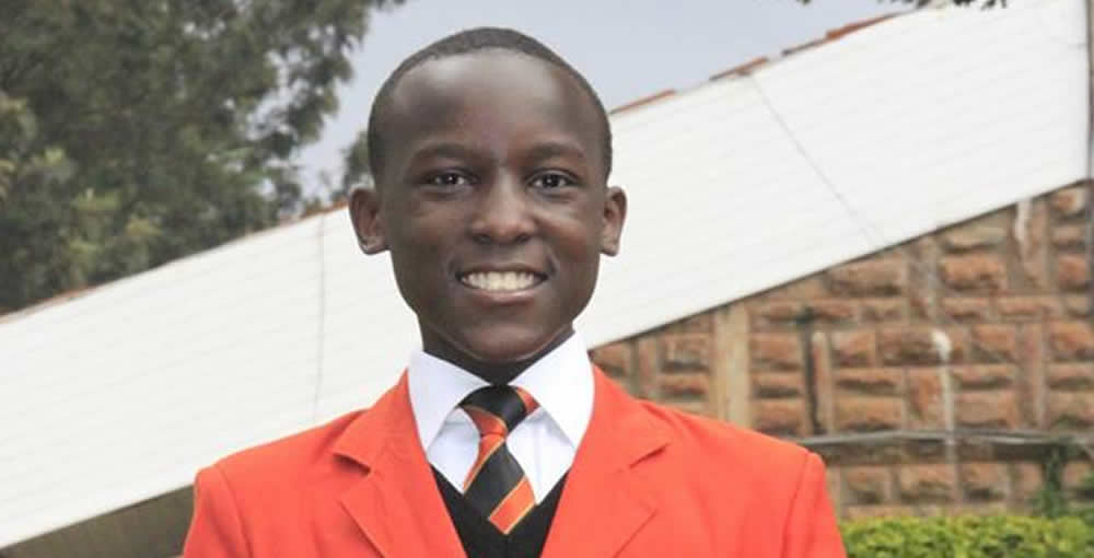 A young man in an orange suit and tie is smiling for the camera.