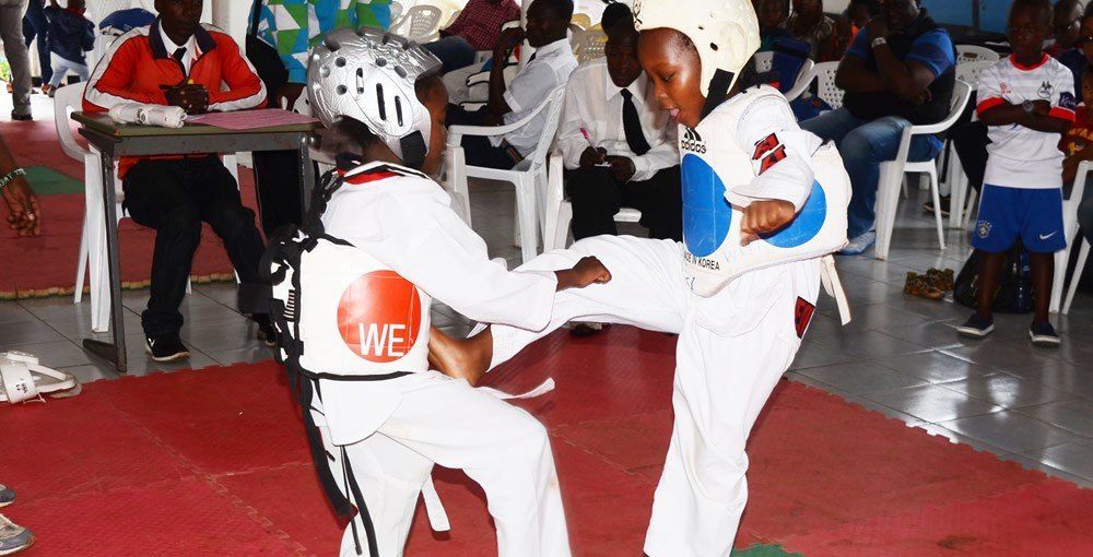 Two people are practicing martial arts on a red mat.