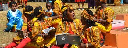 A group of children are sitting on the ground with laptops.