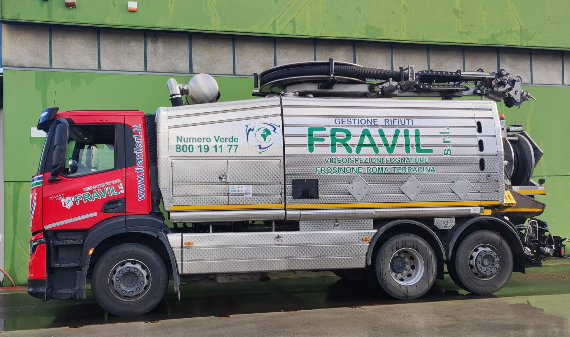 Due tecnici in uniforme blu esaminano un condizionatore fuori da un'abitazione. Davanti a loro ci sono degli attrezzi.
