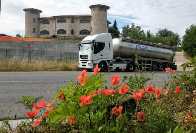 Due tecnici in uniforme blu esaminano un condizionatore fuori da un'abitazione. Davanti a loro ci sono degli attrezzi.