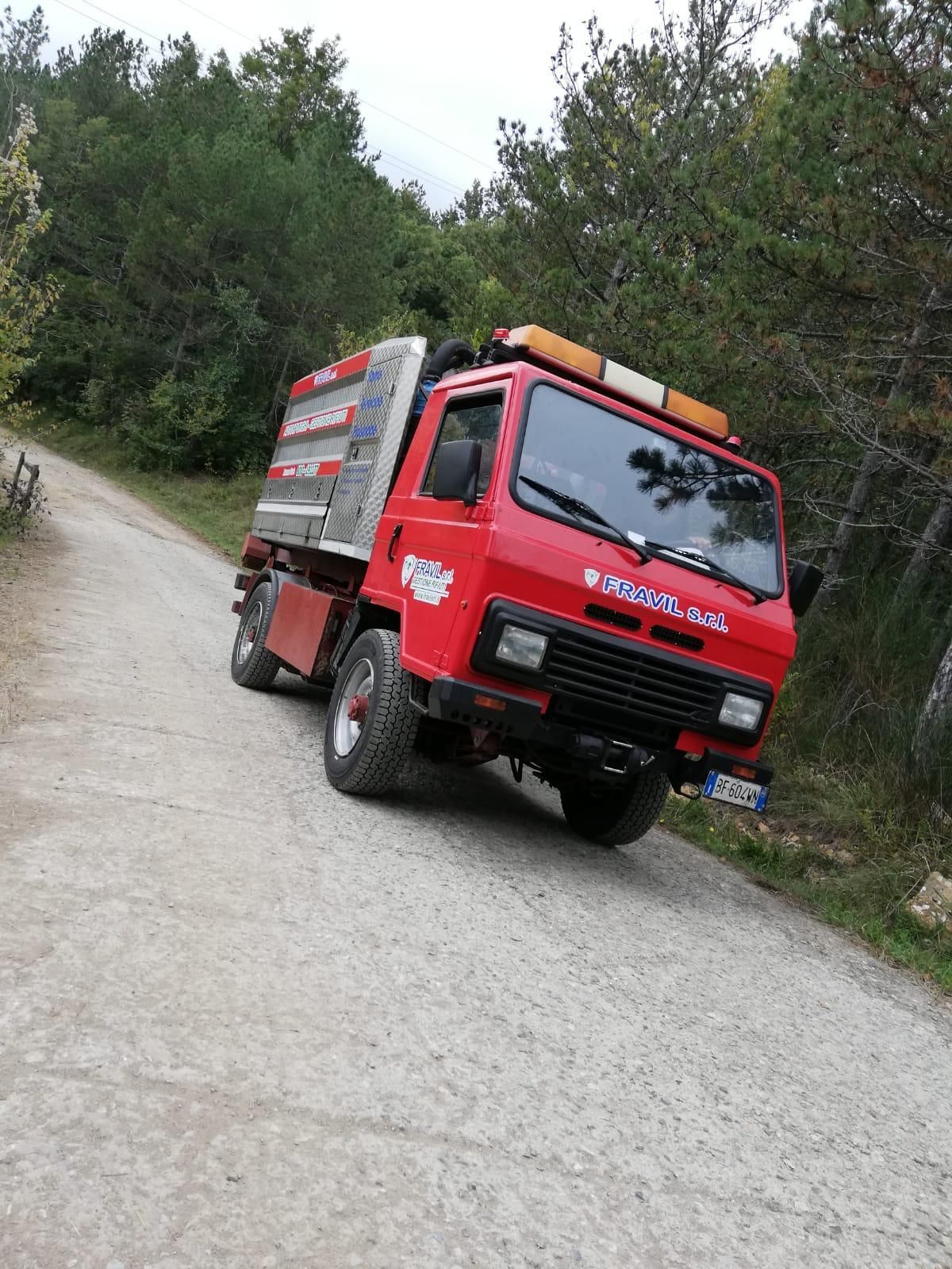 Due tecnici in tuta blu ispezionano un condizionatore d'aria vicino a una finestra.