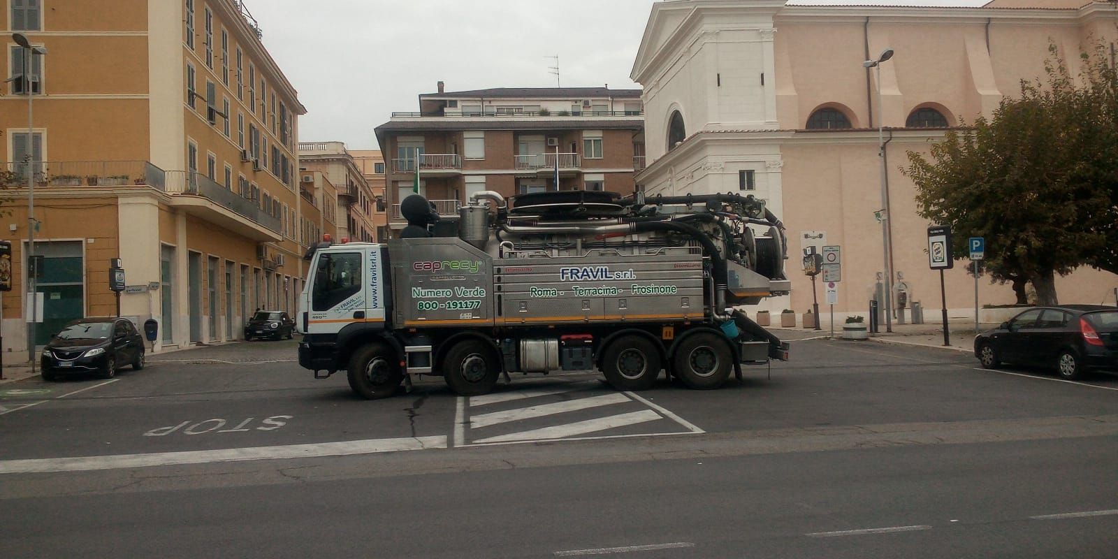Due tecnici in tuta blu ispezionano un condizionatore d'aria vicino a una finestra.