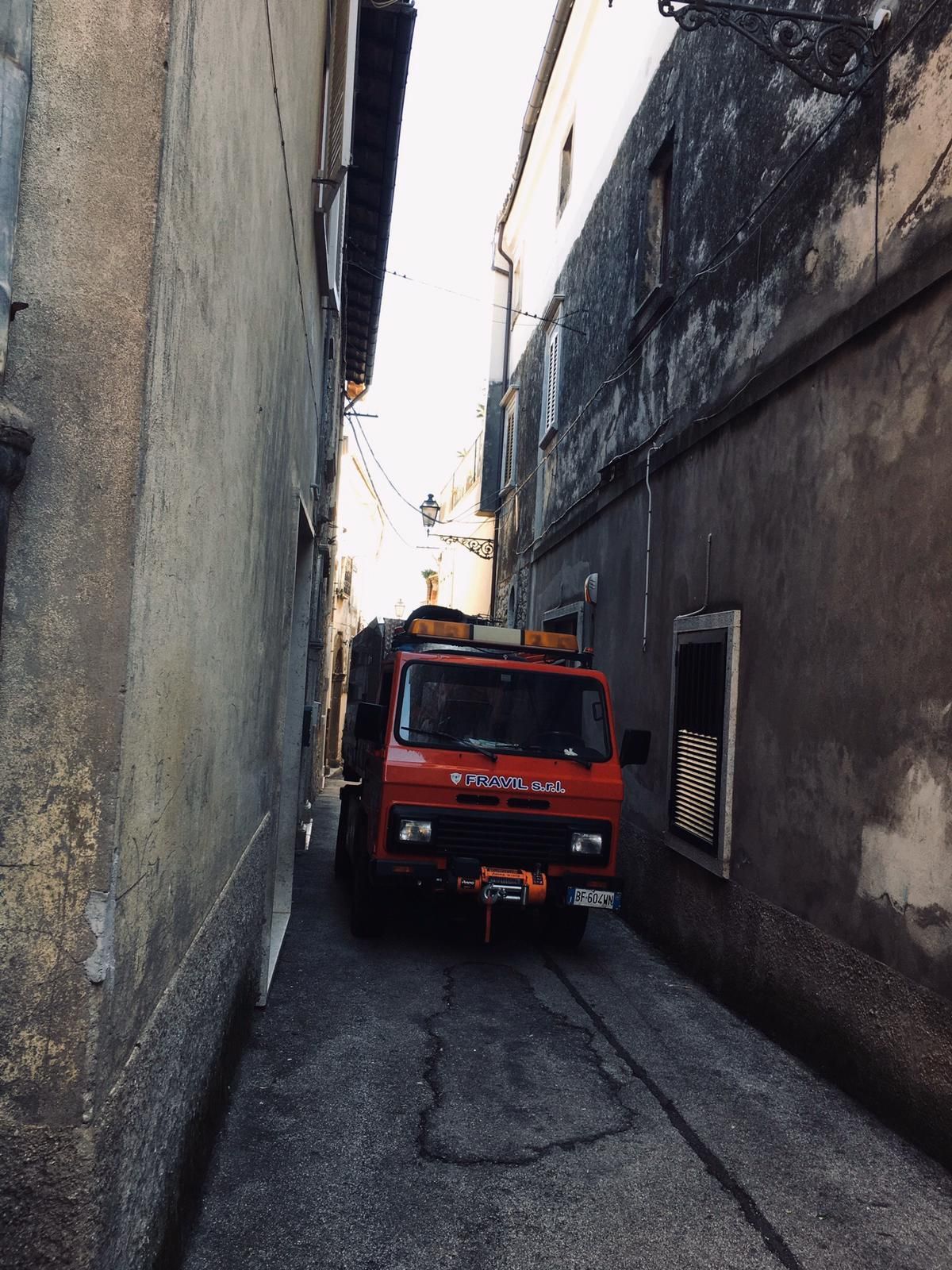 Grande camion industriale argentato sull'erba con cielo sullo sfondo.
