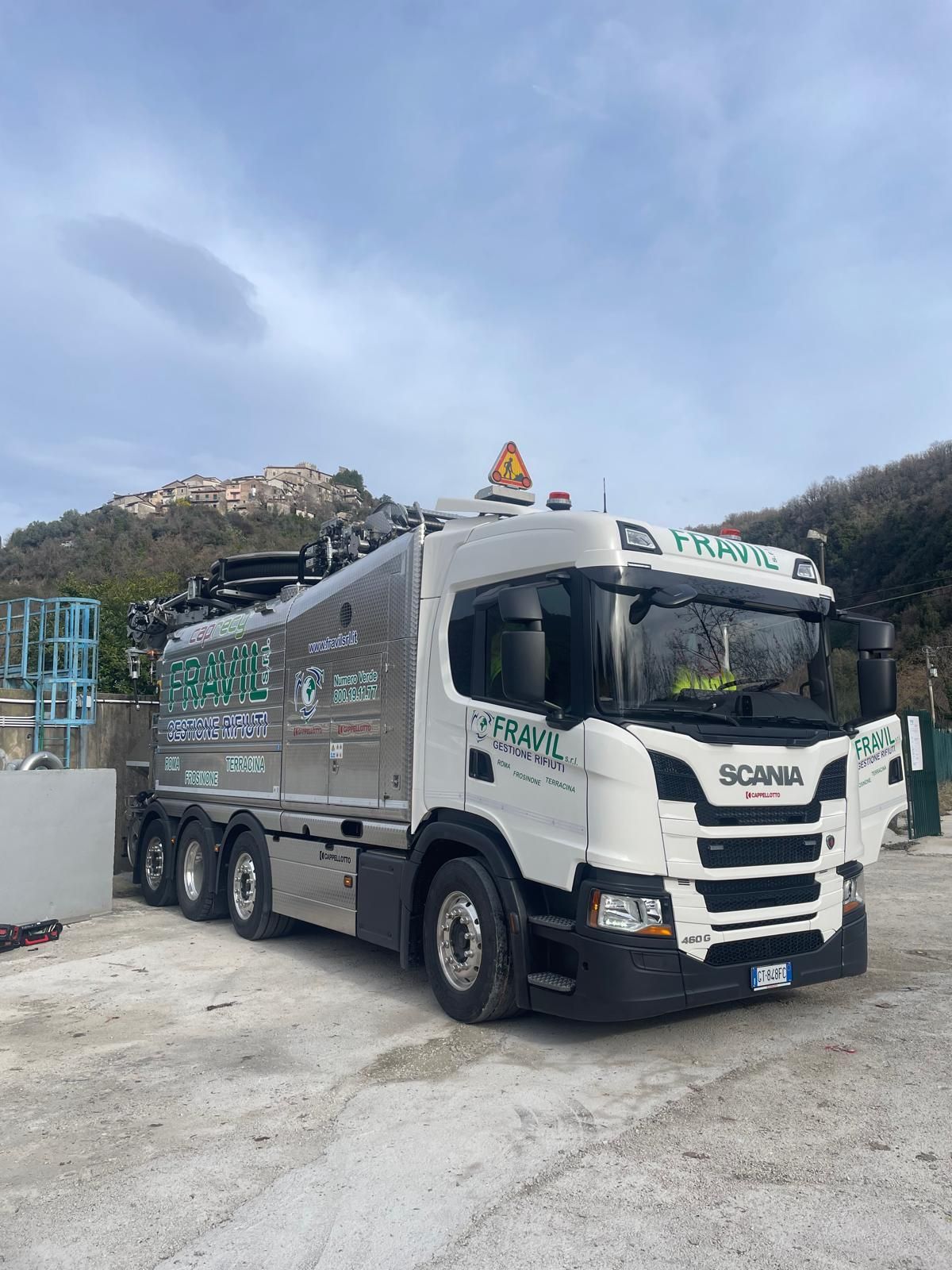 Grande camion industriale argentato sull'erba con cielo sullo sfondo.