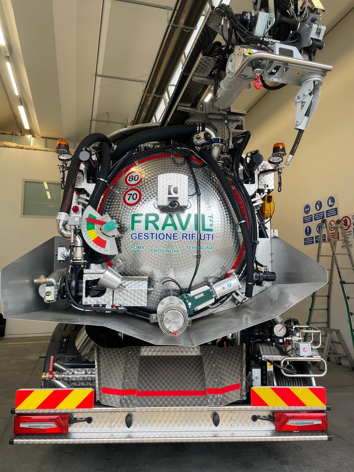 Grande camion industriale argentato sull'erba con cielo sullo sfondo.