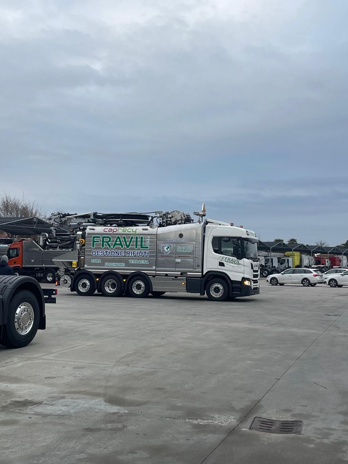 Grande camion industriale argentato sull'erba con cielo sullo sfondo.