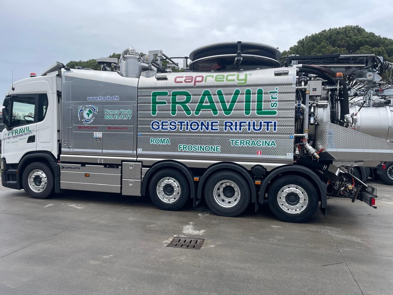 Grande camion industriale argentato sull'erba con cielo sullo sfondo.