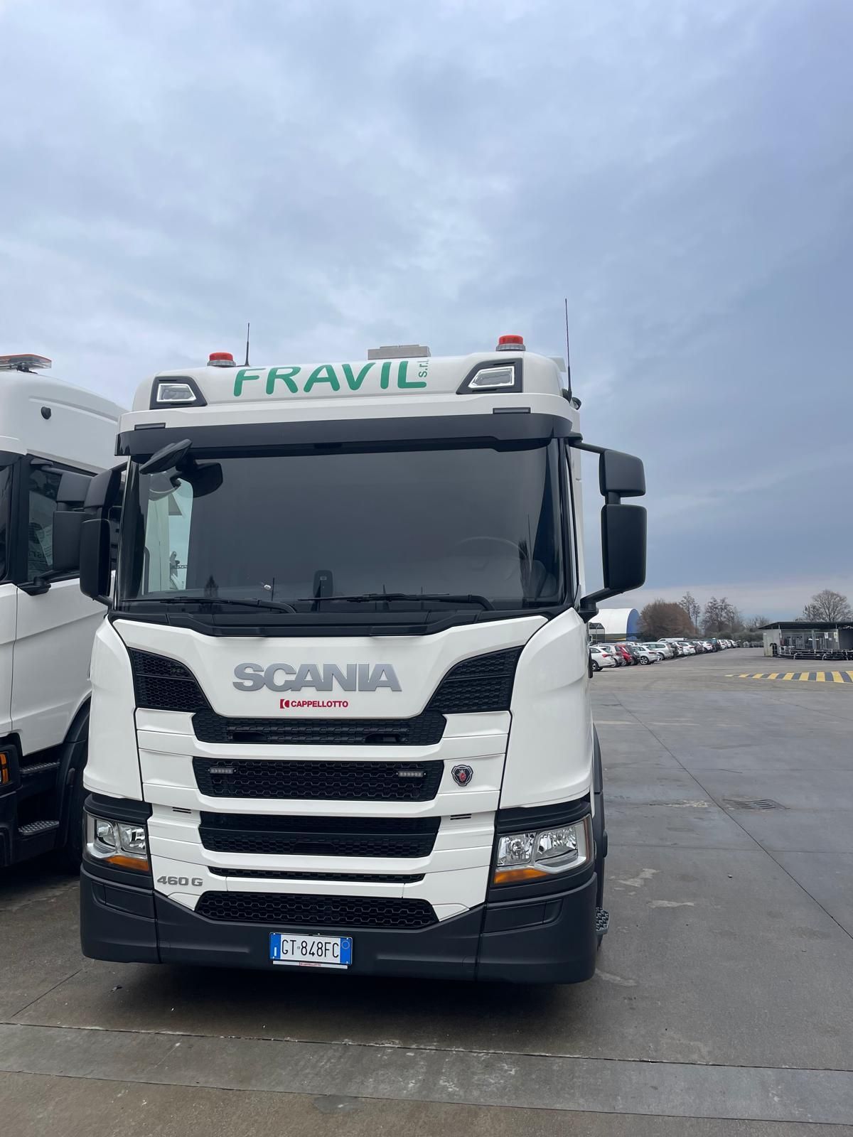 Grande camion industriale argentato sull'erba con cielo sullo sfondo.