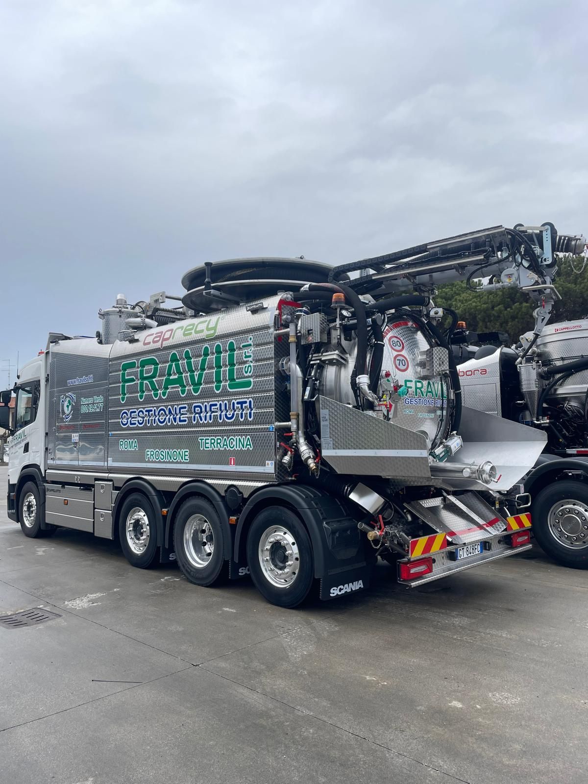 Grande camion industriale argentato sull'erba con cielo sullo sfondo.