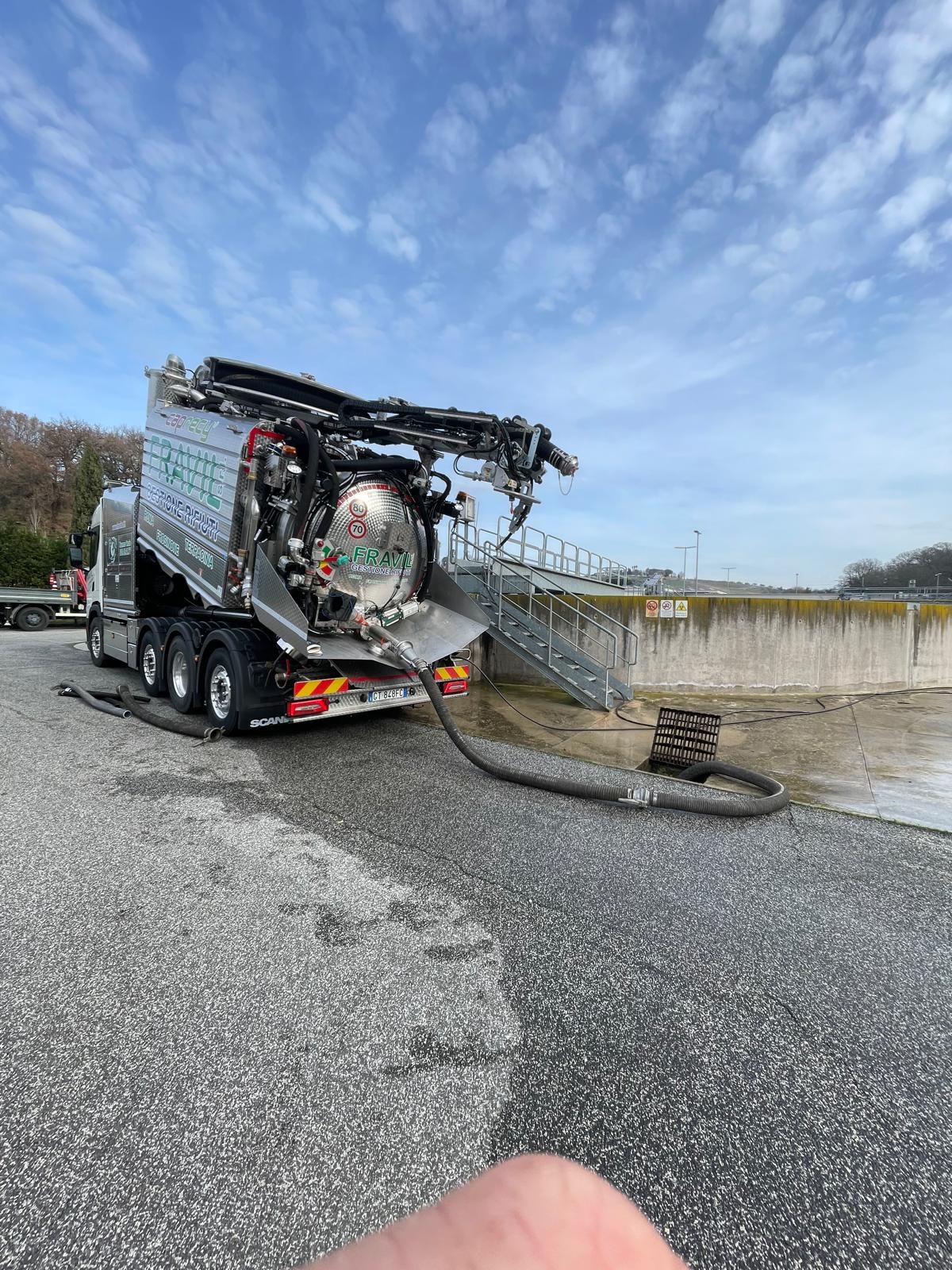Grande camion industriale argentato sull'erba con cielo sullo sfondo.