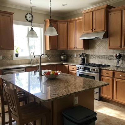 A kitchen with wooden cabinets, a granite countertop island, and stainless steel appliances. Natural light streams in from a window.