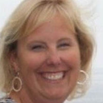 Blonde woman with a warm smile, wearing hoop earrings.