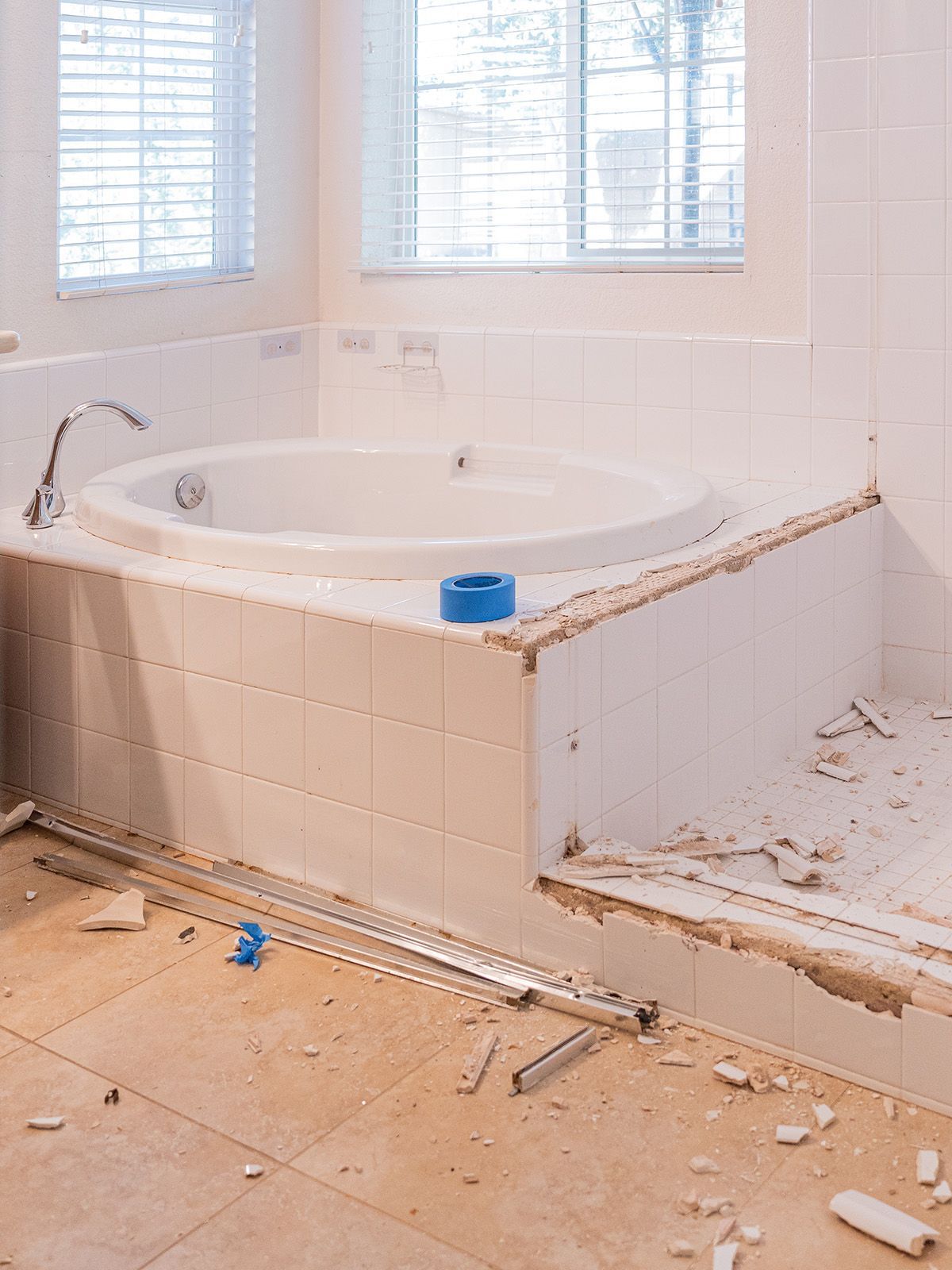 Bathroom with a partially tiled jacuzzi. Construction debris and tools are visible on the floor.