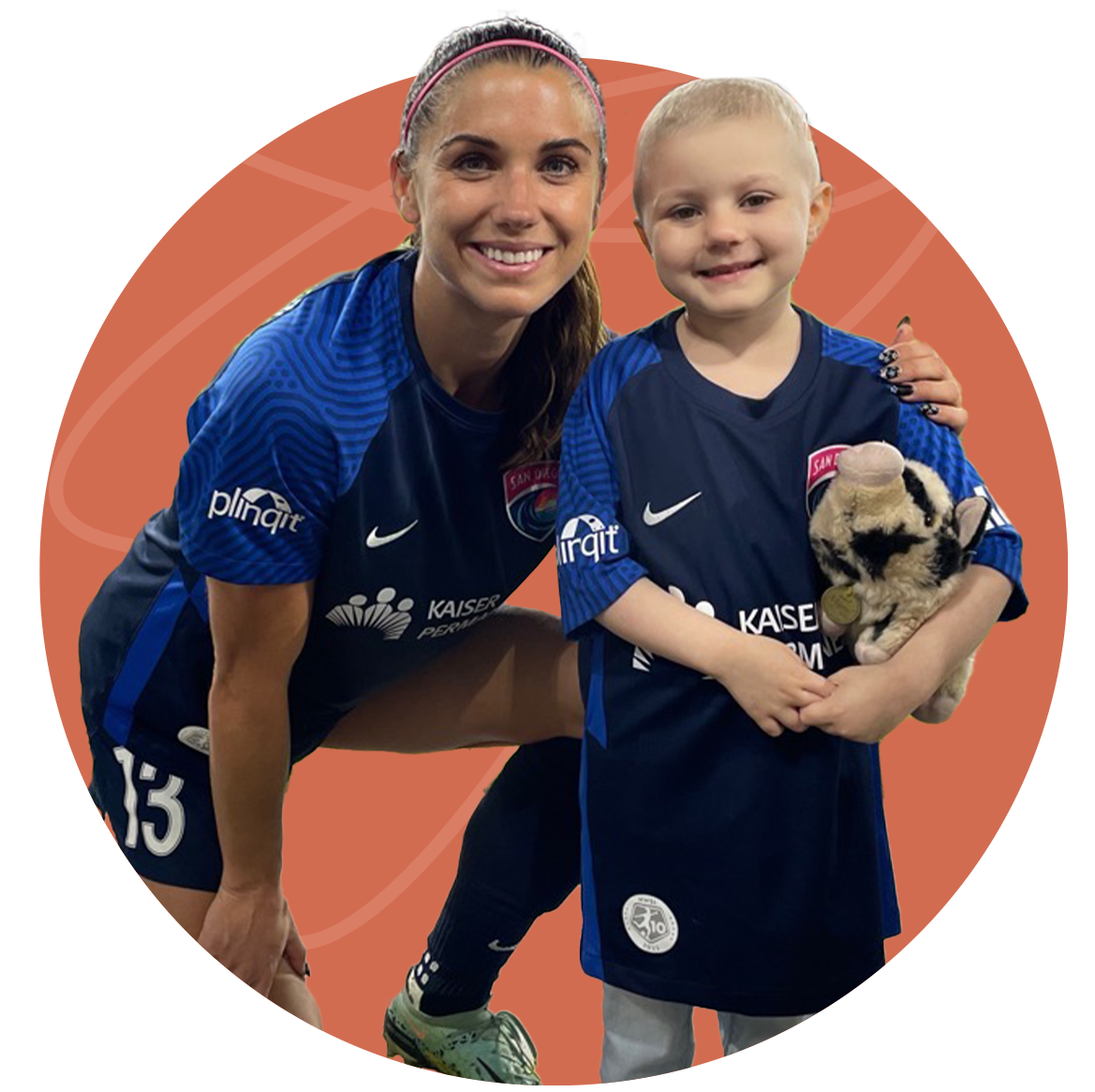 Alex Morgan poses with a young fan in matching soccer jerseys, both smiling. Background is orange with lines.