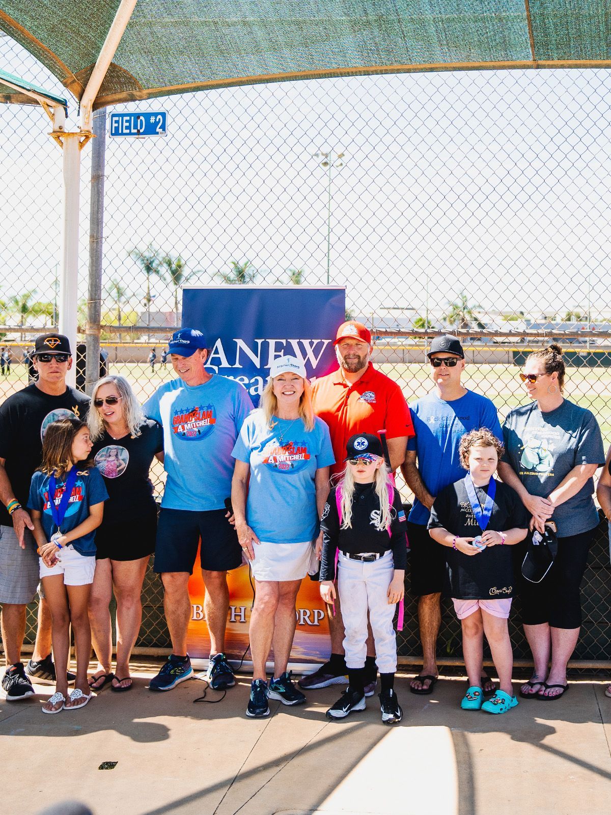 Group of people posing in front of a banner at an outdoor event.