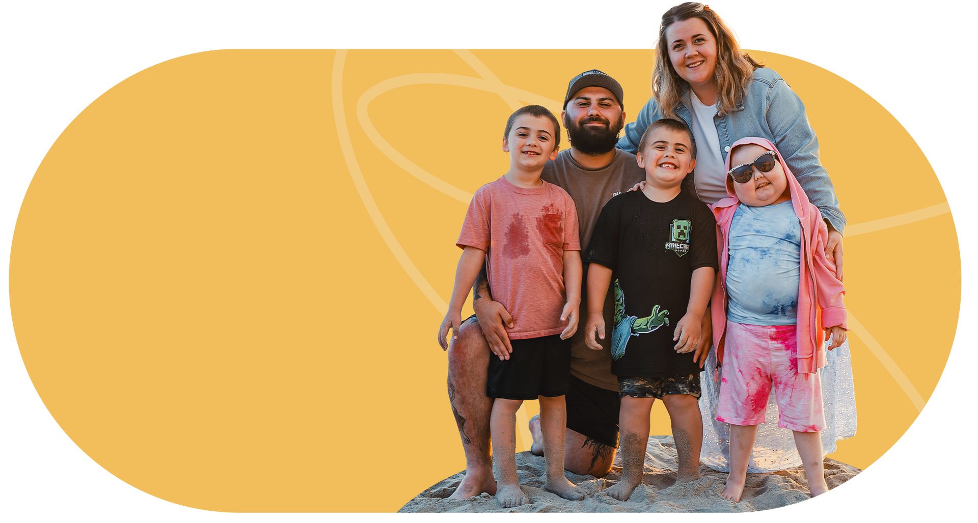 Family of five on a beach. Woman with sunglasses smiles above three young boys and a man, all smiling.