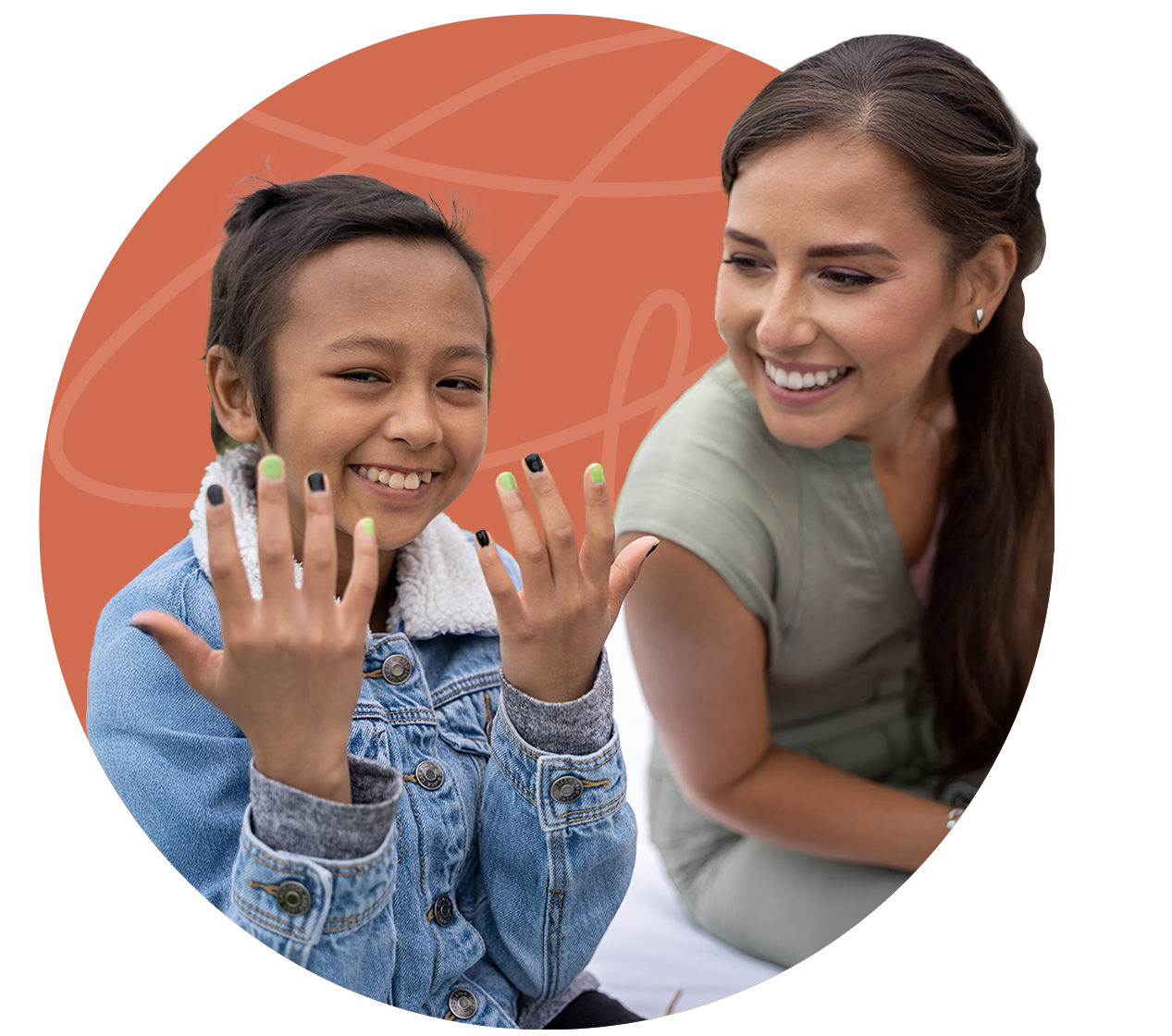 Boy with painted nails smiles, looking at his hands. Woman smiles, watching him. Against orange background.