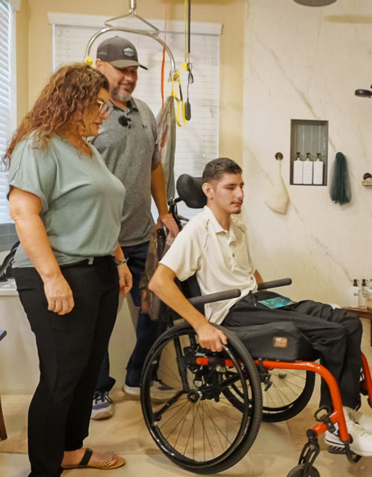 A young man in a wheelchair with family in an accessible bathroom.