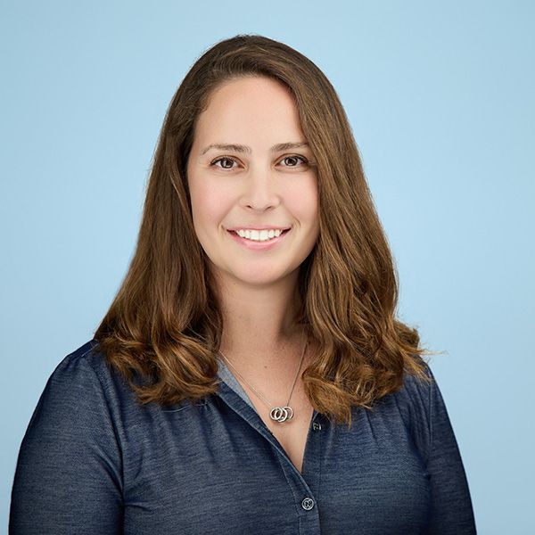 Smiling man in a blue shirt stands outdoors against a golf course backdrop.
