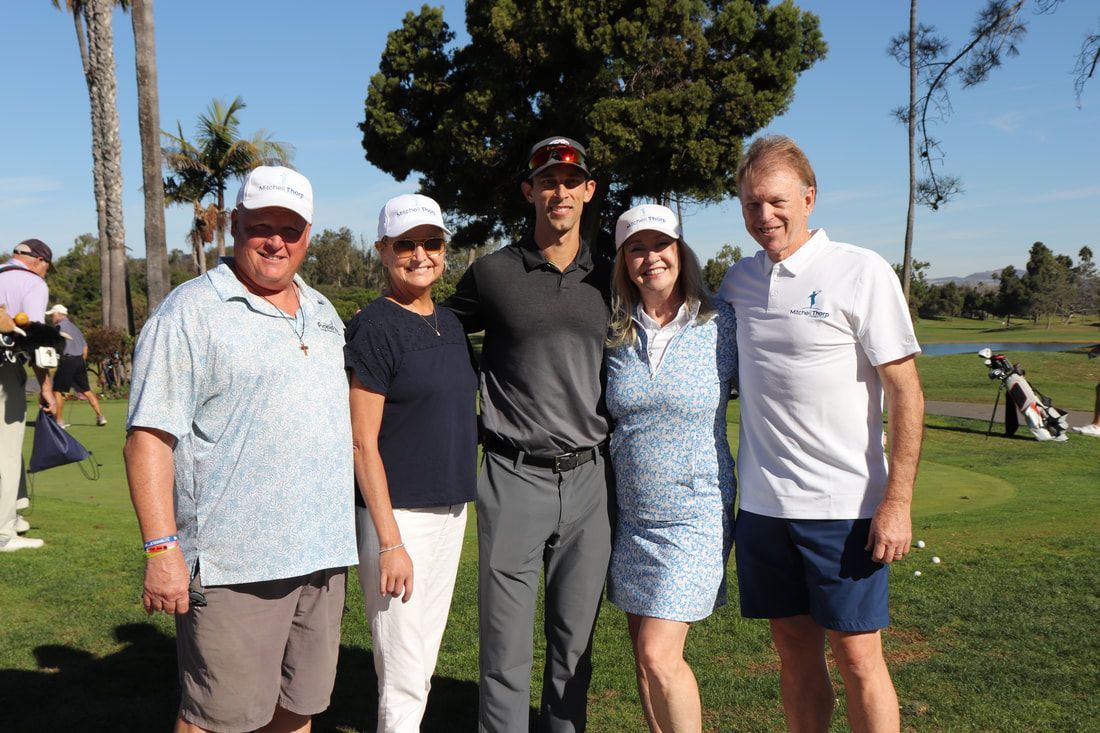 Five people smiling on a golf course. Sunny day, green grass.