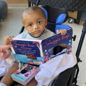 Young child in a wheelchair, reading 