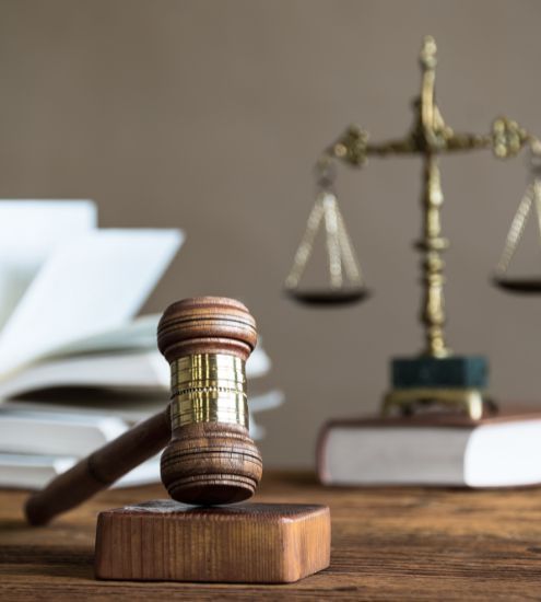 A wooden judge 's gavel is sitting on a wooden table next to a scale of justice.