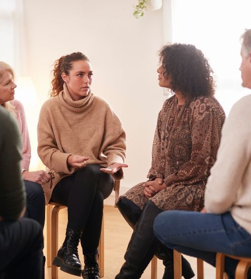 A group of people are sitting in a circle talking to each other.