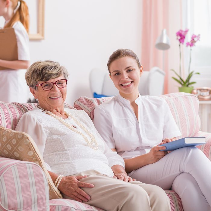 Two women are sitting on a couch and smiling for the camera.