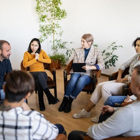 A group of people are sitting in chairs in a circle.