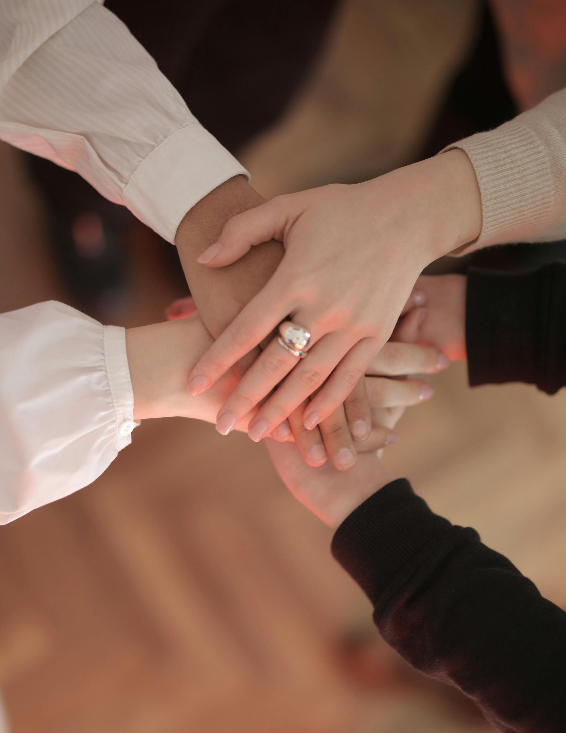 A close-up view of several people stacking their hands on top of each other in a gesture of unity.