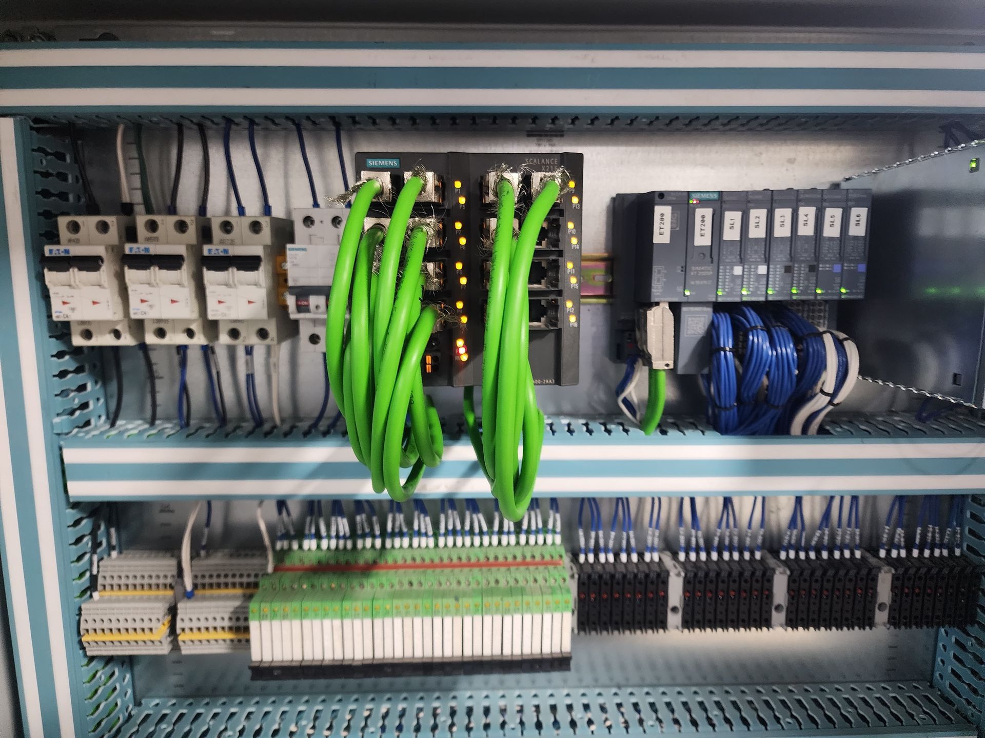 Panel de control con componentes eléctricos: disyuntores, cableado y un PLC.