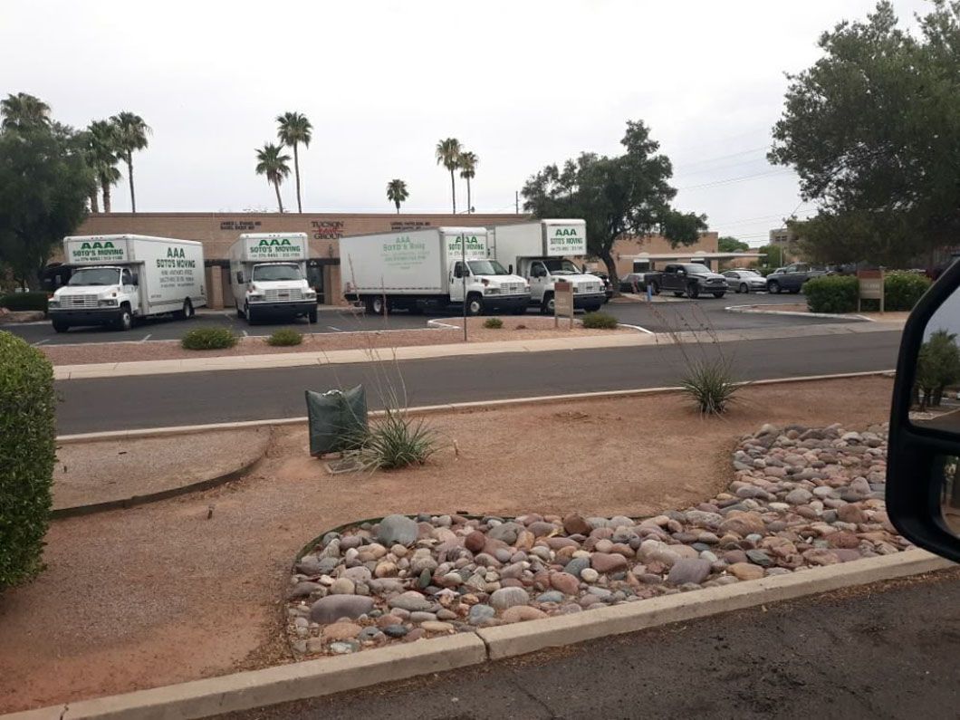 A row of moving trucks are parked on the side of the road