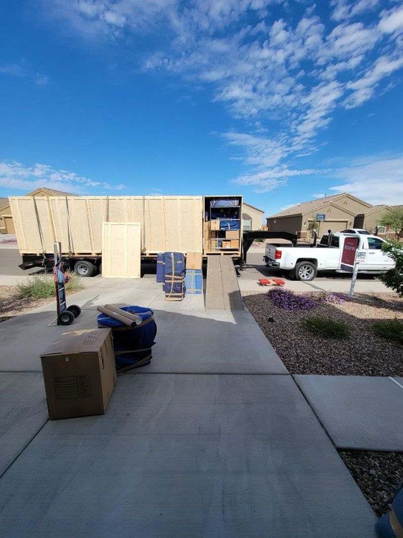 A white truck is parked in front of a house with boxes on the sidewalk.