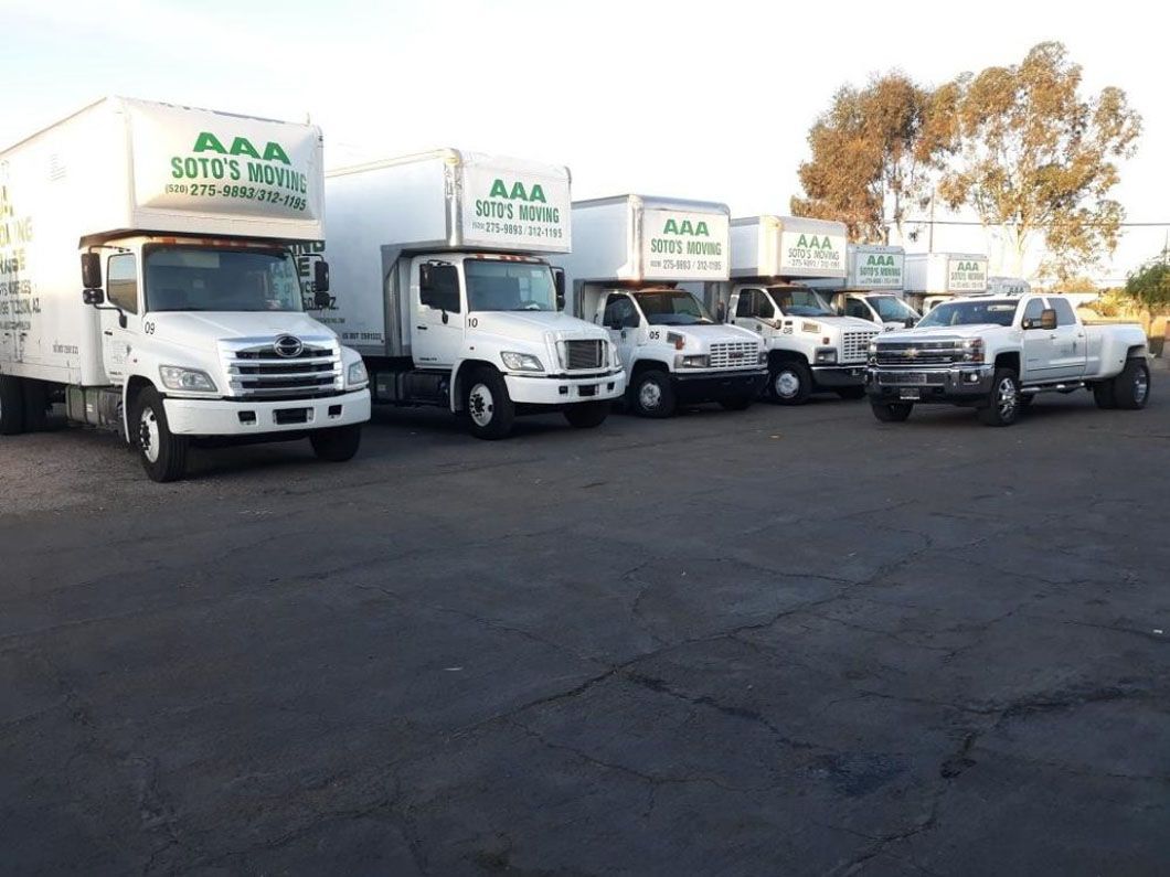 A row of aaa moving trucks are parked in a parking lot