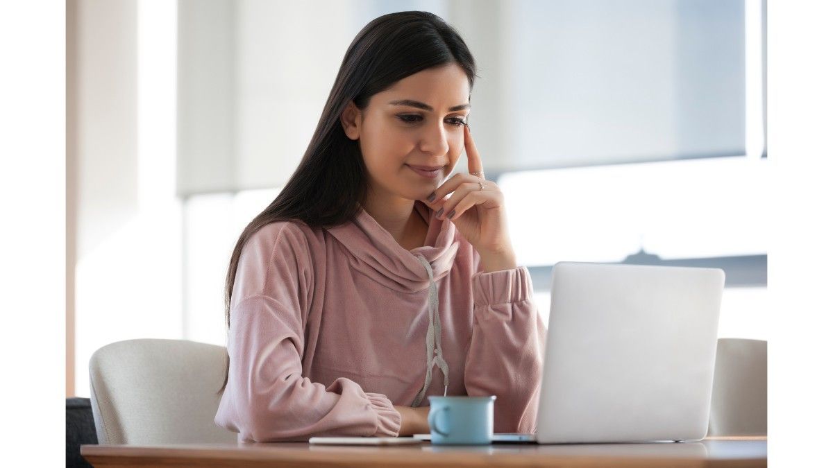 A woman is sitting at a table using a laptop computer.