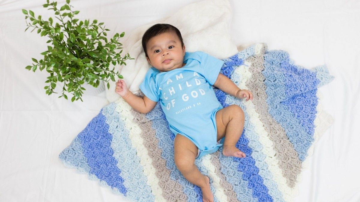 A baby is laying on a blue and white striped blanket.