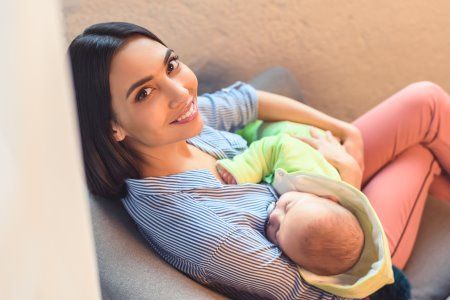 A woman is breastfeeding her baby while sitting on a couch.